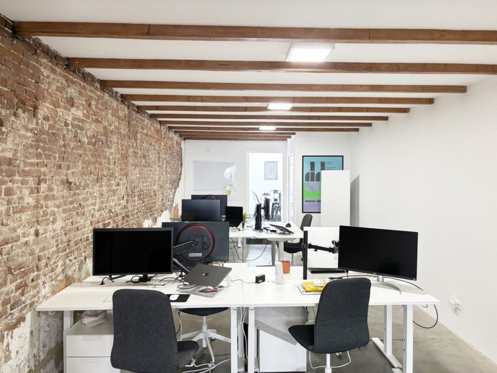 Modern open-plan office space on Van Ostadestraat with exposed brick wall, white desks, and computer workstations.